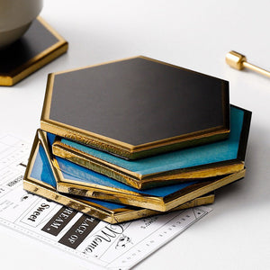 Stack of hexagonal ceramic coasters by Audacem on a table