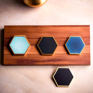 Hexagonal ceramic coasters by Audacem in various colors on a wooden board