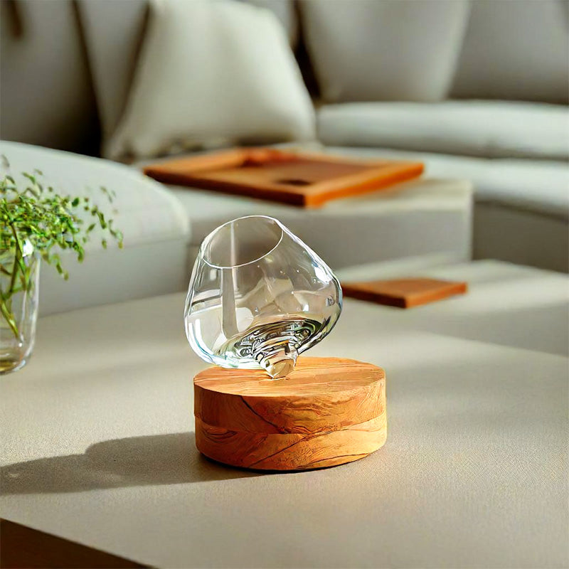 Hand-blown Aequilibrium wine glass on wooden base in modern living room setting – premium glassware designed to enhance aroma and balance.