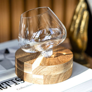 Aequilibrium wine glass on a handcrafted wooden coaster by Audacem on a bookshelf