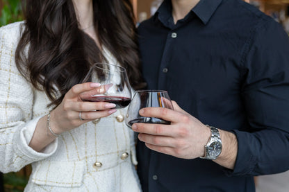 Aequilibrium Wine Glasses by Audacem held by couple making romantic toast, hand-blown glassware with red wine in elegant setting